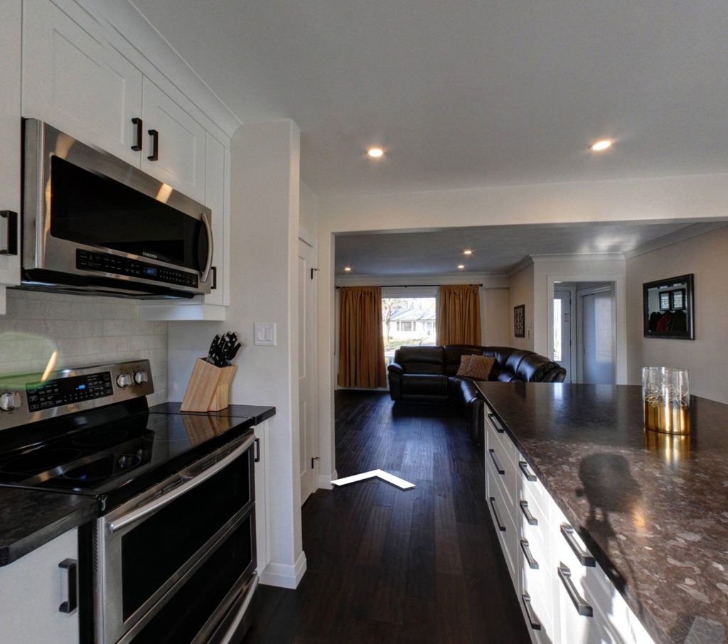 Kitchen renovation with dark granite countertops, white cabinets and a black stainless steel microwave and stove/oven