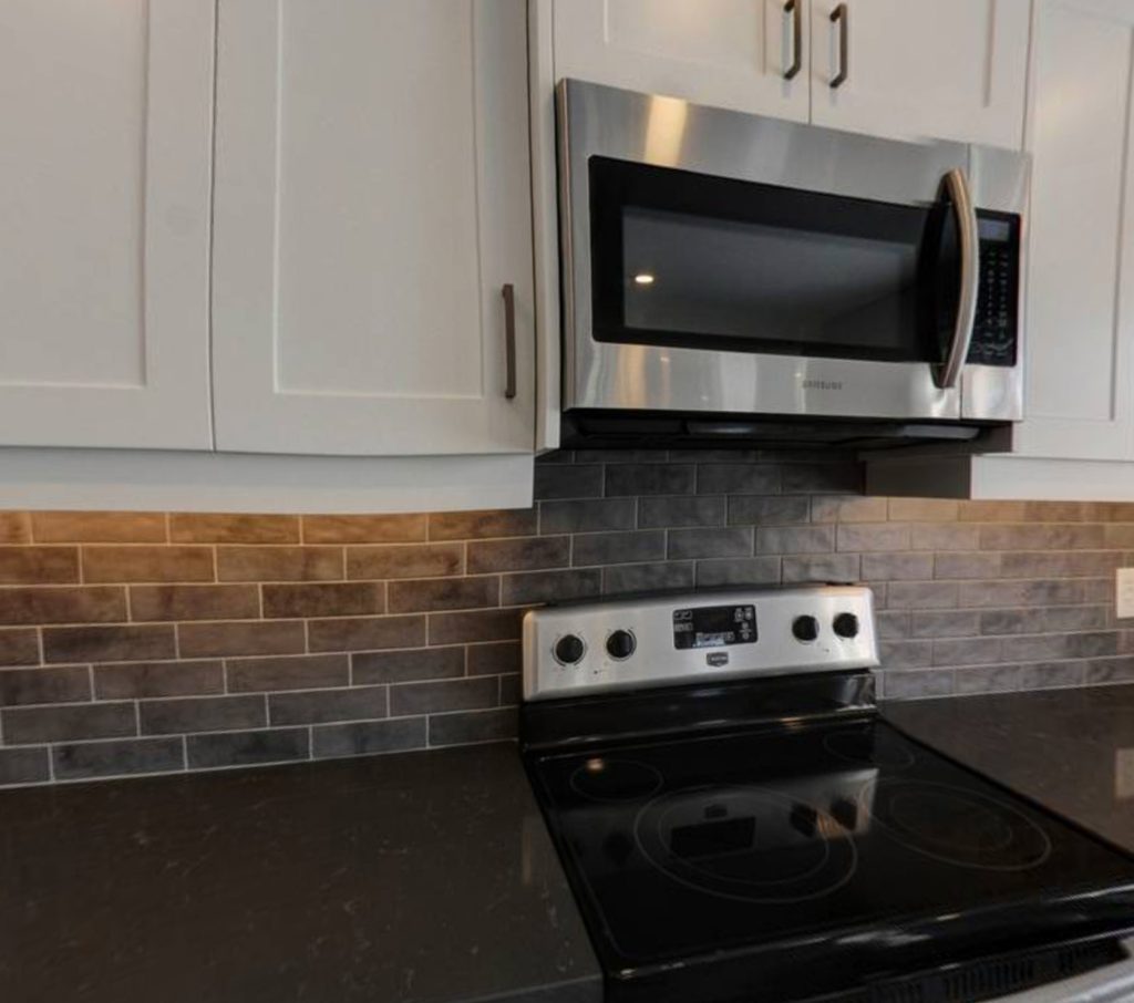 Kitchen renovation with black granite countertop, white cabinets and a grey tile backsplash
