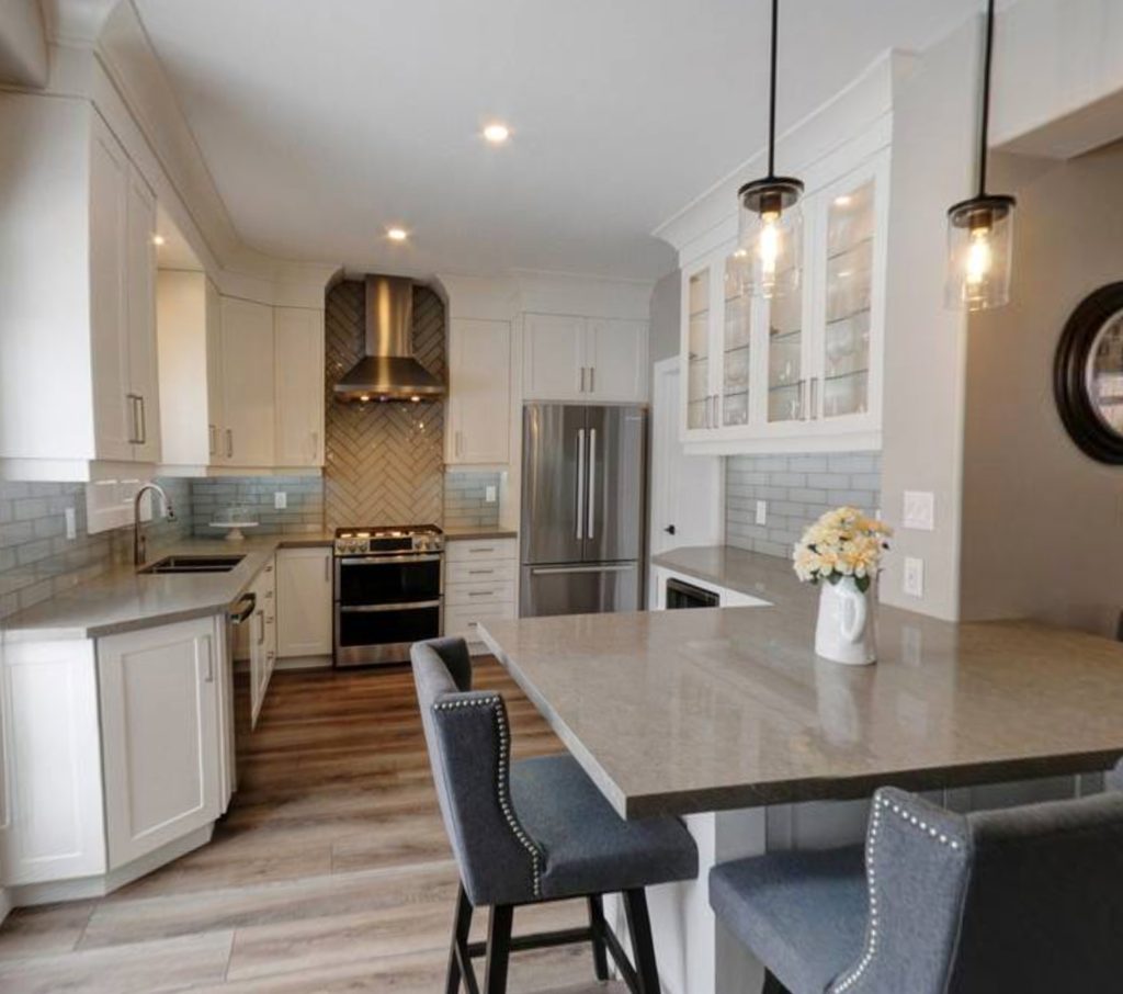 Kitchen renovation with grey granite countertops, white cabinets and grey tile backsplash
