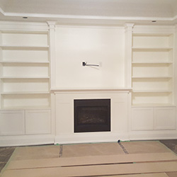 Fireplace renovation with white frame, white cabinets and white shelving