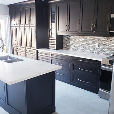 Kitchen renovation with white counter tops, black cabinets and a multicolour tile backsplash
