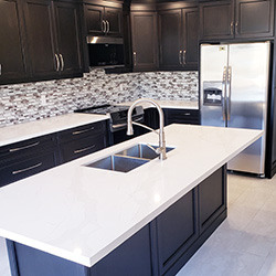 Kitchen renovation with white counter tops, black cabinets and a matching kitchen island